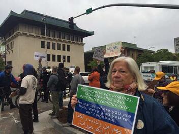 Deborah Cohen holds a sign welcoming refugees.